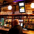 A digital poster shows an Uber ad in a London pub