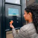 Woman tapping bank card on screen on wall