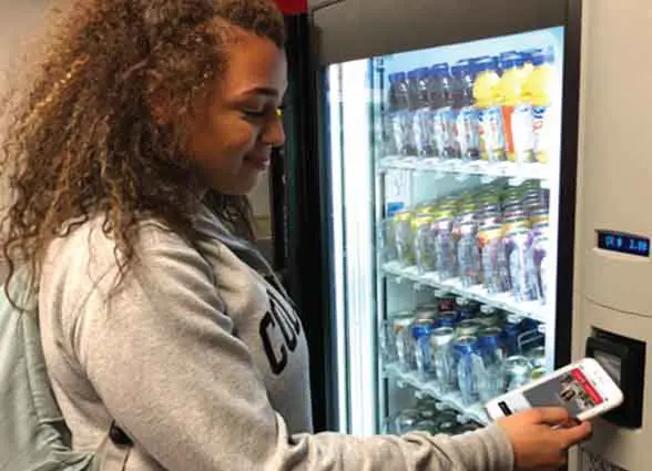 Woman using nfc phone to buy item from vending machine