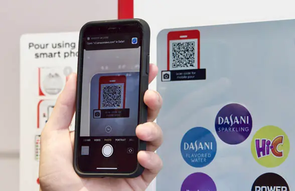 Coca-Cola Freestyle contactless drinks dispenser showing phone with qr code