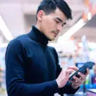 Man using smartphone to make payment using mobile wallet in store