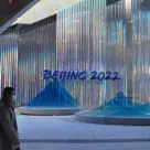Person walking past sign for Beijing Winter Olympics
