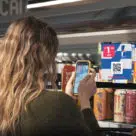 woman using personalised digital vouchers on smartphone in Nisa store