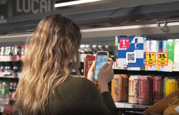 woman using personalised digital vouchers on smartphone in Nisa store