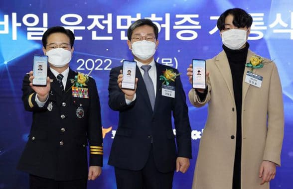 Men holding smartphones showing South Korea's mobile driving licences