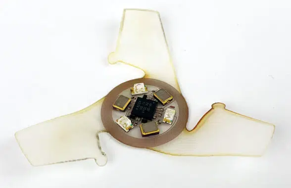 Closeup of miniature batteryless flying microchips with NFC