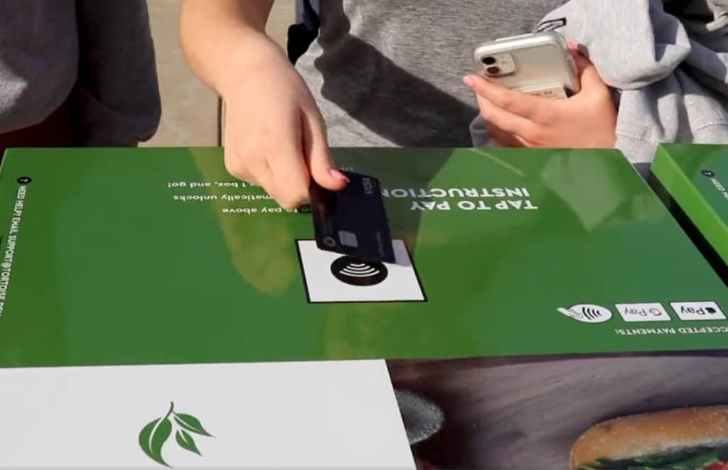 Customer using contactless card to buy from Tortoise robotic mobile smart store in the US