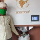 Man standing next to automated biometric commodity dispensers for distributing subsidised food in India