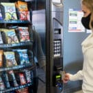 Woman making cashless contactless purchase from vending machine in the USA