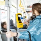 Woman on bus making contactless visa payment with phone