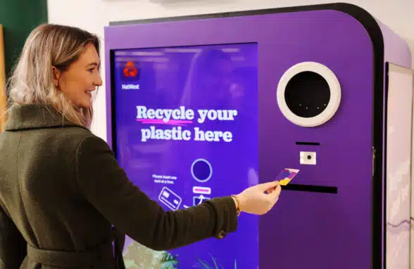Woman using NatWest reverse vending machine that lets consumers recycle unwanted payment cards