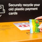 Woman putting card into Mastercard plastic bank card recycling box in a branch of HSBC