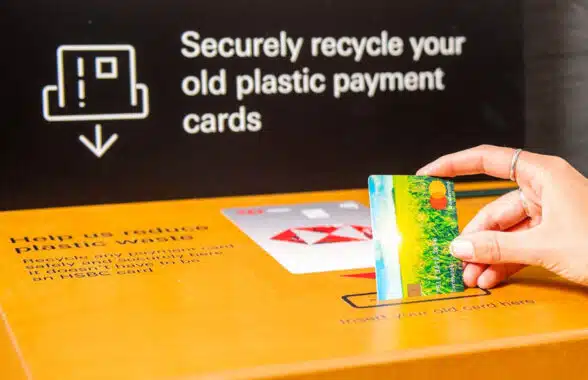 Woman putting card into Mastercard plastic bank card recycling box in a branch of HSBC