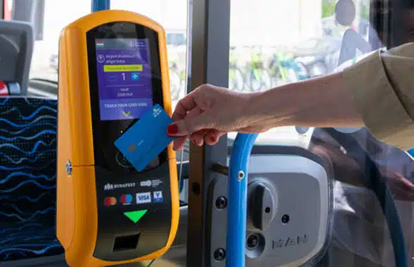 Person using bank card to make open loop contactless fare payments on airport shuttle bus in Budapest