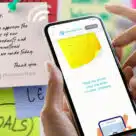 Person holding an NFC phone over a Memento Note smart sticky note