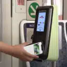 Person using smartphone on a validator on a Toronto bus to make open loop contactless fare payment