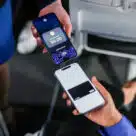 Customer making contactless payment on a Alaska Airlines' flight attendant's iPhone using Apple Tap to Pay