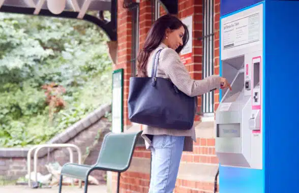 Woman buying a ticket from machine at a railway station in London